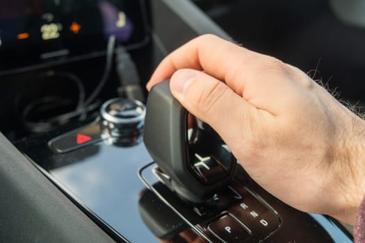 PRAGUE , CZECH REPUBLIC - MARCH 10 2022: Man shifts mode on automatic transmission of new electric car Polestar 2. Luxury modern automobile with stylish interior design closeup