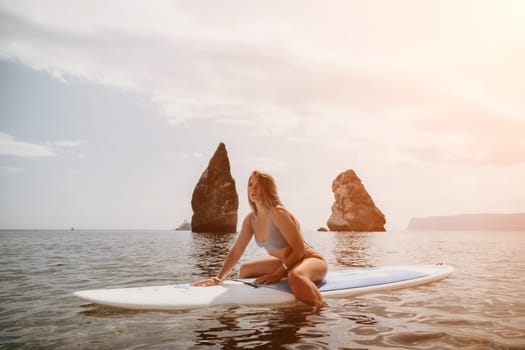 Close up shot of beautiful young caucasian woman with black hair and freckles looking at camera and smiling. Cute woman portrait in a pink bikini posing on a volcanic rock high above the sea