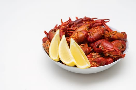 Fresh red boiled crayfish food on a plate on a white background. Healthy seafood snack with lemon.