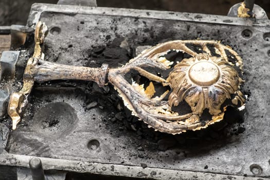 Stylish brass flower with branches in molding form cast in traditional way in ancient production plant workshop extreme close view