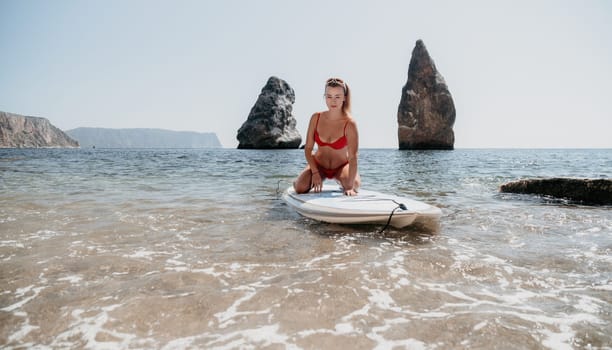 Close up shot of beautiful young caucasian woman with black hair and freckles looking at camera and smiling. Cute woman portrait in a pink bikini posing on a volcanic rock high above the sea