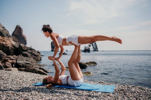 Woman sea yoga. Back view of free calm happy satisfied woman with long hair standing on top rock with yoga position against of sky by the sea. Healthy lifestyle outdoors in nature, fitness concept.