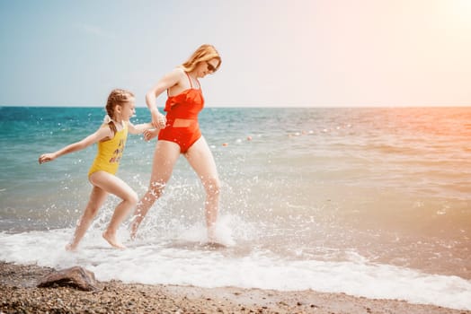 Happy loving family mother and daughter having fun together on the beach. Mum playing with her kid in holiday vacation next to the ocean - Family lifestyle and love concept.