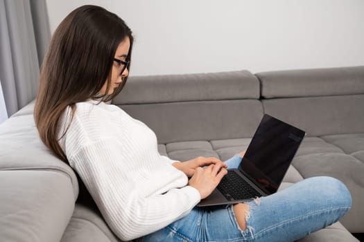 Side view of long hair woman working remotely via the internet at home.