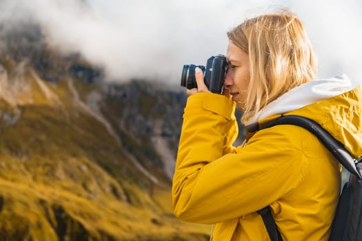 Close up pretty girl taking photos of mountains in Italian Alps on a retro camera.