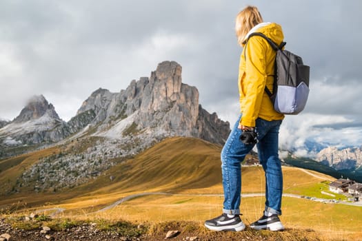 Happy female tourist enjoys in Italian Alps. Young woman feels happy to see Passo Giau pass in haze