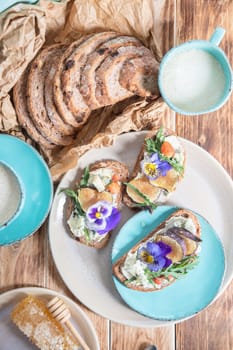 delicious bruschetta with homemade bread, garnished with fig,soft cheese,pansies, top view. High quality photo