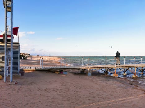 Man stands on the pier and takes pictures of paragliding. Seascape with photographer