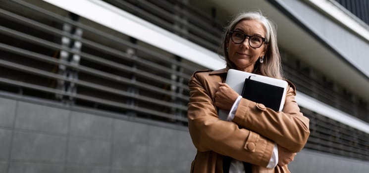 portrait of a successful business mature businesswoman with a laptop in her hands outside the office.