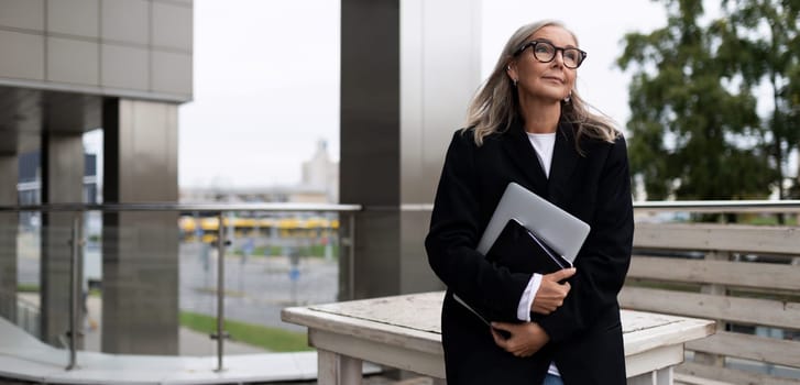 Business woman on the terrace of an office building with a laptop in her hands.