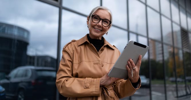 elderly stylish woman with a tablet on the background of a business center.