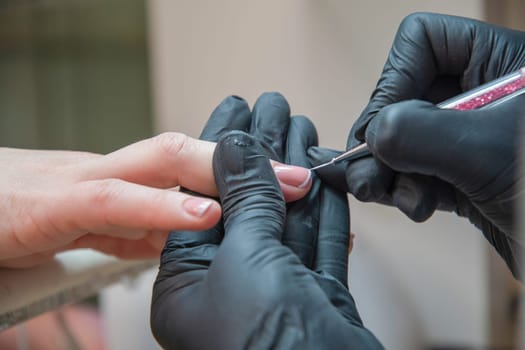 A master manicurist makes a drawing french manicure nails using white varnish and a thin brush, Manicure process, High quality photo