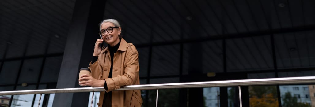 elderly business woman talking on mobile phone outside.