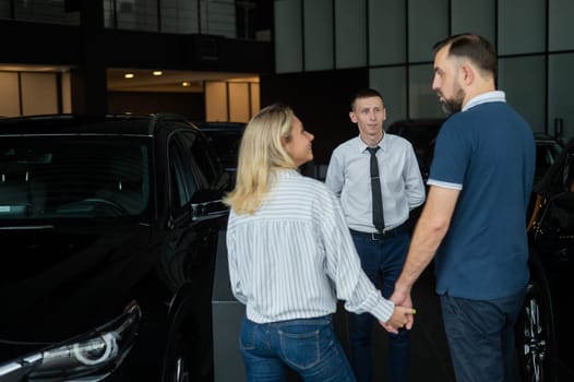 Happy caucasian couple choosing a new car in a car dealership