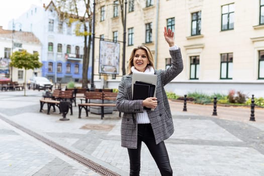 businesswoman catches a taxi in the city with a laptop in her hands.