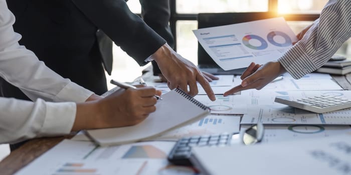 Diverse businesspeople cooperate work together discussing company financial statistics, multiracial colleagues employees collaborate brainstorm with finance document at meeting. close up shot.