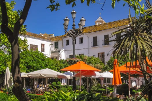 A picturesque restaurant with many trees and umbrellas in the old town of Marbella in Andalusia, Spain