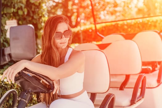 A middle-aged woman is driving a car for transporting tourists. Electric car, Tourist bus. Car for transporting people around the hotel, park.