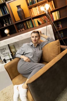 woman resting in a comfortable position Sitting in an easy chair on the background of the home library.