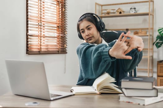 Asian young student in casual video call and doing stretch oneself from study online class. Online distance e-learning education concept.