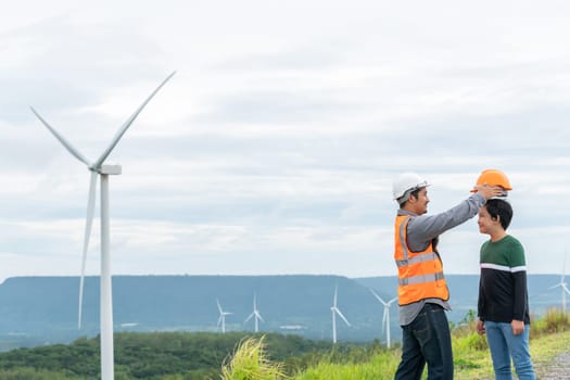 Engineer with his son on a wind farm atop a hill or mountain in the rural. Progressive ideal for the future production of renewable, sustainable energy. Energy generation from wind turbine.