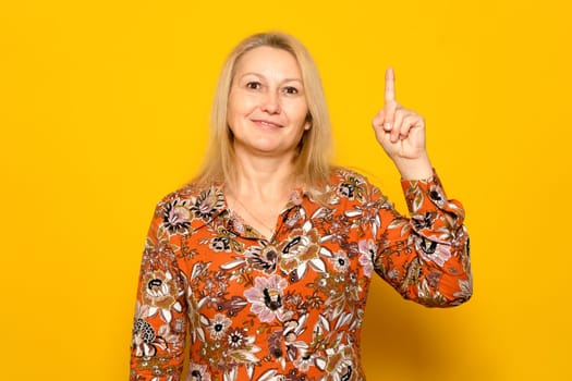Inspiration, Creativity, Solution, Eureka concept. Portrait of excited caucasian blonde woman in patterned dress raising finger up and smiling, having amazing creative idea, yellow studio background
