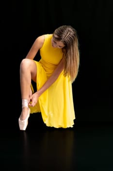 ballerina lacing her shoes, portrait on a black background. High quality photo