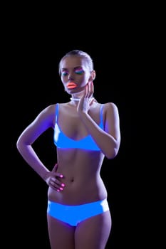 Seductive slim girl posing with ultraviolet makeup, isolated on black