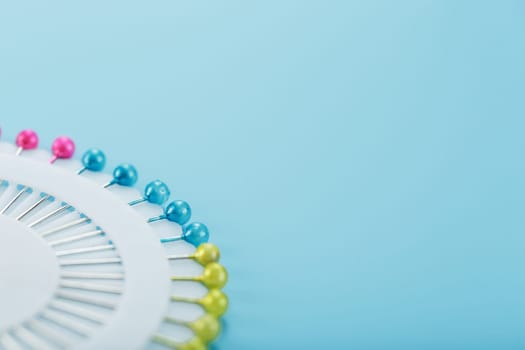 Sewing mother-of-pearl pins in a round white package on a blue background with free space