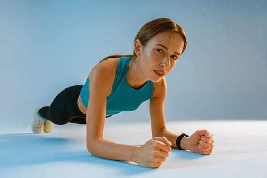 Fit Woman standing in plank position on studio background. High quality photo