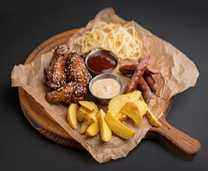 Baked chicken wings served with different sauces and lemon. Black background