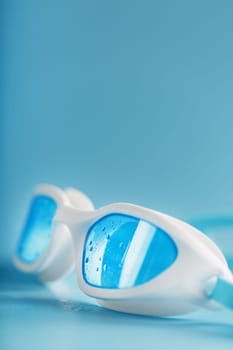 White swimming goggles on a blue background in a minimalist style with free space