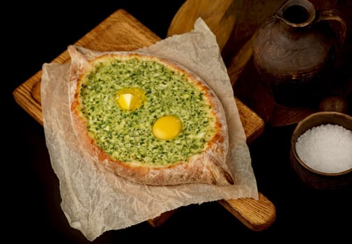 Traditional georgian pastry - adjarian khachapuri with cheese and raw yolk. Khachapuri with egg on wooden background in rustic style. Adjara khachapuri with ingredients.