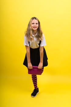 Little teenager girl with pencil case on a yellow background