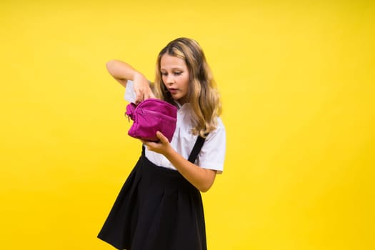 Little teenager girl with pencil case on a yellow background