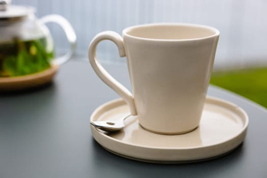 A steaming hot cup of tea sits on a saucer atop a wooden table, inviting refreshment with its comforting aroma.