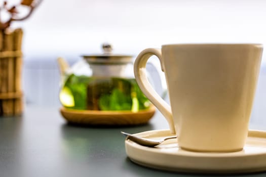A steaming hot cup of tea sits on a saucer atop a wooden table, inviting refreshment with its comforting aroma.