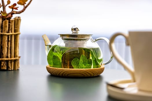 A steaming teapot of fragrant mint tea sits on a table outdoors, the perfect accompaniment to a healthy meal.