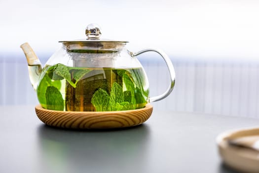 A steaming teapot of fragrant mint tea sits on a table outdoors, the perfect accompaniment to a healthy meal.