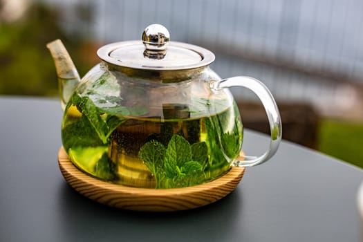 A steaming teapot of fragrant mint tea sits on a table outdoors, the perfect accompaniment to a healthy meal.