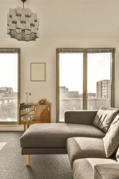 a living room with two windows and a large couch in front of the window looking out to the city skyline