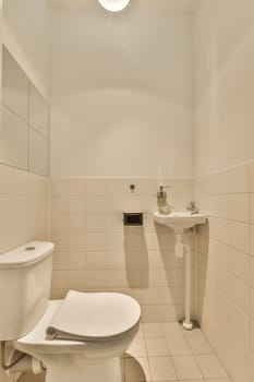 a bathroom with white tile and beige tiles on the walls, along with a toilet in the center of the room