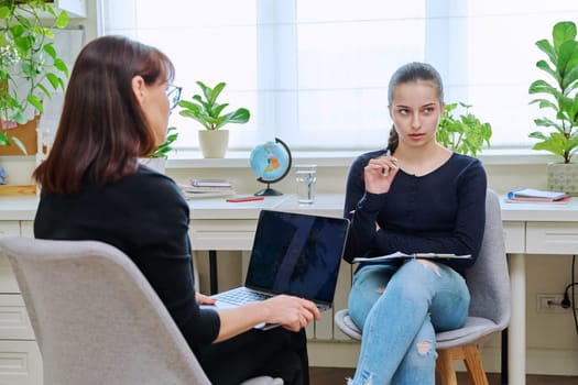 Teenage girl high school student talking with counselor, mentor, psychologist, social worker in the office. Adolescence, mental health, socialization, counseling, advice, psychology, therapy concept
