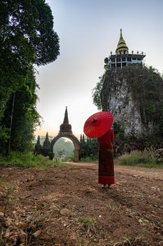 Women in Thai national costumes  With the red umbrella standing in front of the main door, the time of waiting, the past image, the time gate  Translation at the door is the name: "Putthawadee"