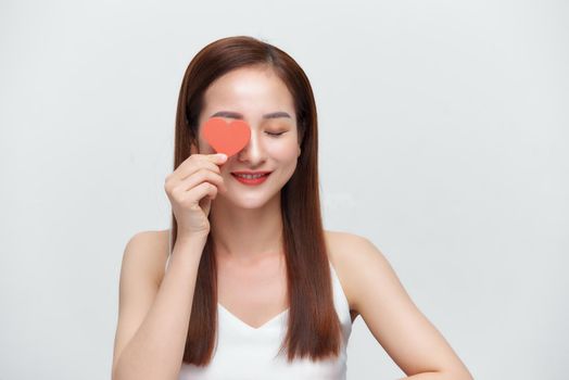 Attractive young woman holding red love hearts over eyes isolated on white background