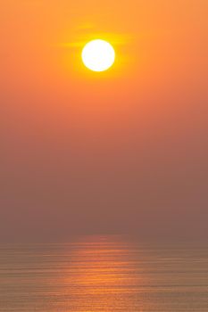 Sunset, the sea surface, reflecting the sun in orange. Clear sky, cloudless orange