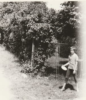 THE CZECHOSLOVAK SOCIALIST REPUBLIC - CIRCA 1980s: Vintage photo shows a small boy holds Frisbee. Retro black and white photography. Circa 1980.