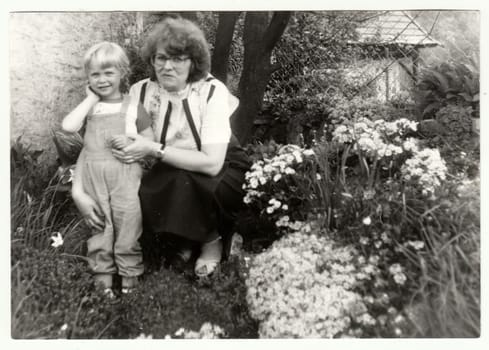 THE CZECHOSLOVAK SOCIALIST REPUBLIC - CIRCA 1980s: Vintage photo shows woman with a small girl in the garden. Holidays in the summertime. Retro black and white photography. Circa 1980.