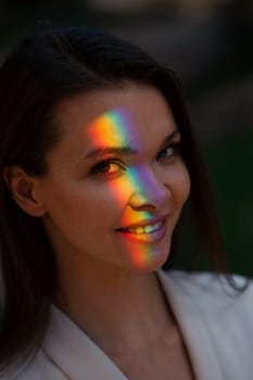 Portrait of caucasian woman with rainbow beam on her face outdoors
