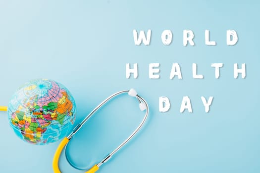 World Health Day. Top view yellow doctor stethoscope wrapped around world globe isolated on pastel blue background with copy space for text, Save world day, Health care and medical concept